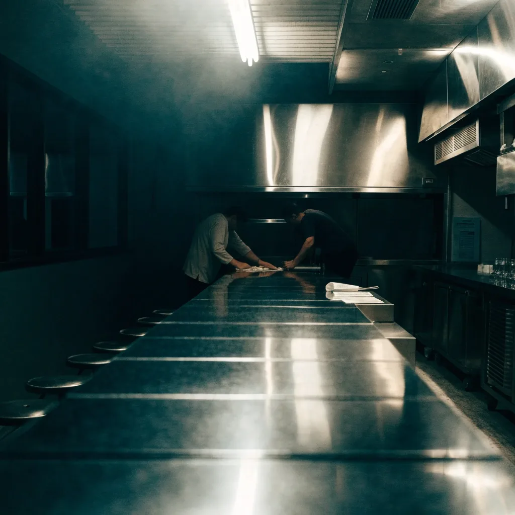 Empty overnight diner counter under fluorescent light, order ticket resting on the pass
